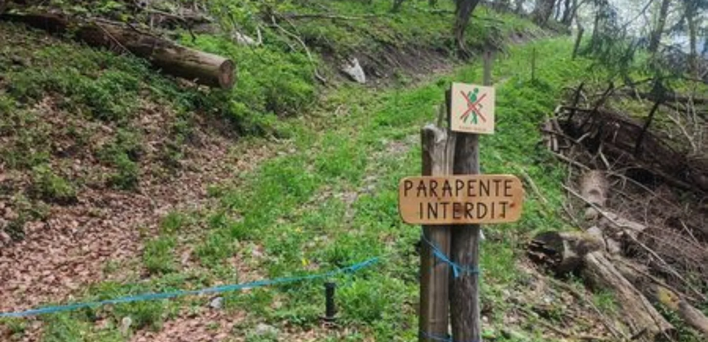 Un panneau d'interdiction à destination des parapentistes sur un chemin de randonnée